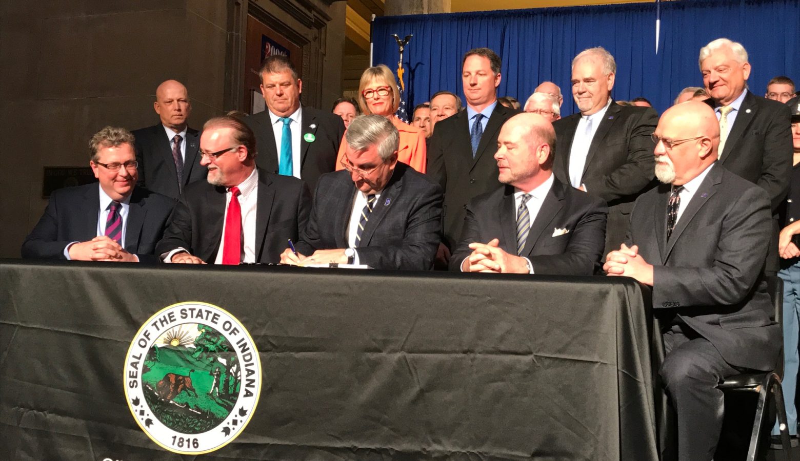 Governor Eric Holcomb, surrounding by lawmakers, signs into law a new $32 billion, two-year state budget. (Brandon Smith/IPB News)