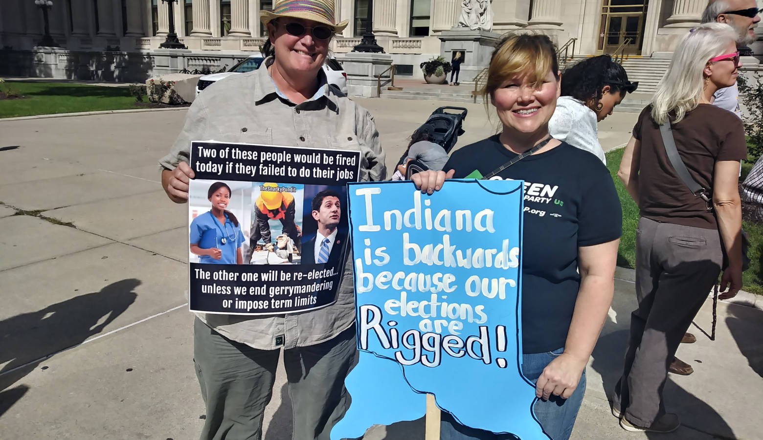 Two advocates hold up their signs in front of the federal courthouse in Indianapolis. (Lauren Chapman/IPB News)