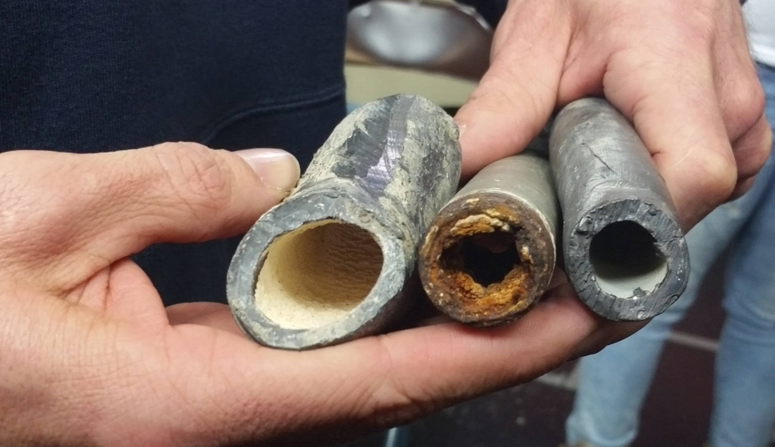 EPA project manager Robert Durno demonstrates the visual difference between orthophosphate-coated lead pipes, corroded lead pipes, and lead pipes with their original coating. (Lauren Chapman/IPB News)