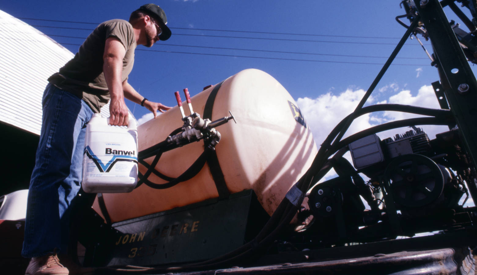 An old photo of a man filling a sprayer tank with Banvel, a brand name for dicamba herbicide in 1985. (USDA NRCS)