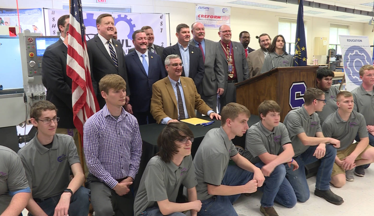 Gov. Eric Holcomb and legislators pose with students at Seymour High School after signing a career and technical education bill into law. (Zachary Herndon/WTIU)