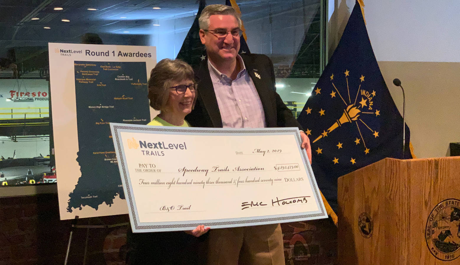 Gov. Eric Holcomb poses with the head of the Speedway Trails Association, which received the single largest award from the first round of the Next Level Trails program. (Brandon Smith/IPB News)