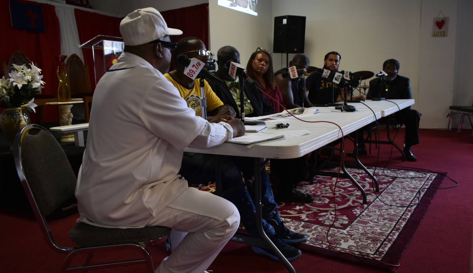 Family members of Eric Logan, city council members, and others sit on a panel at a radio station to discuss the investigation of Logan's death. (IPBS News / Justin Hicks)