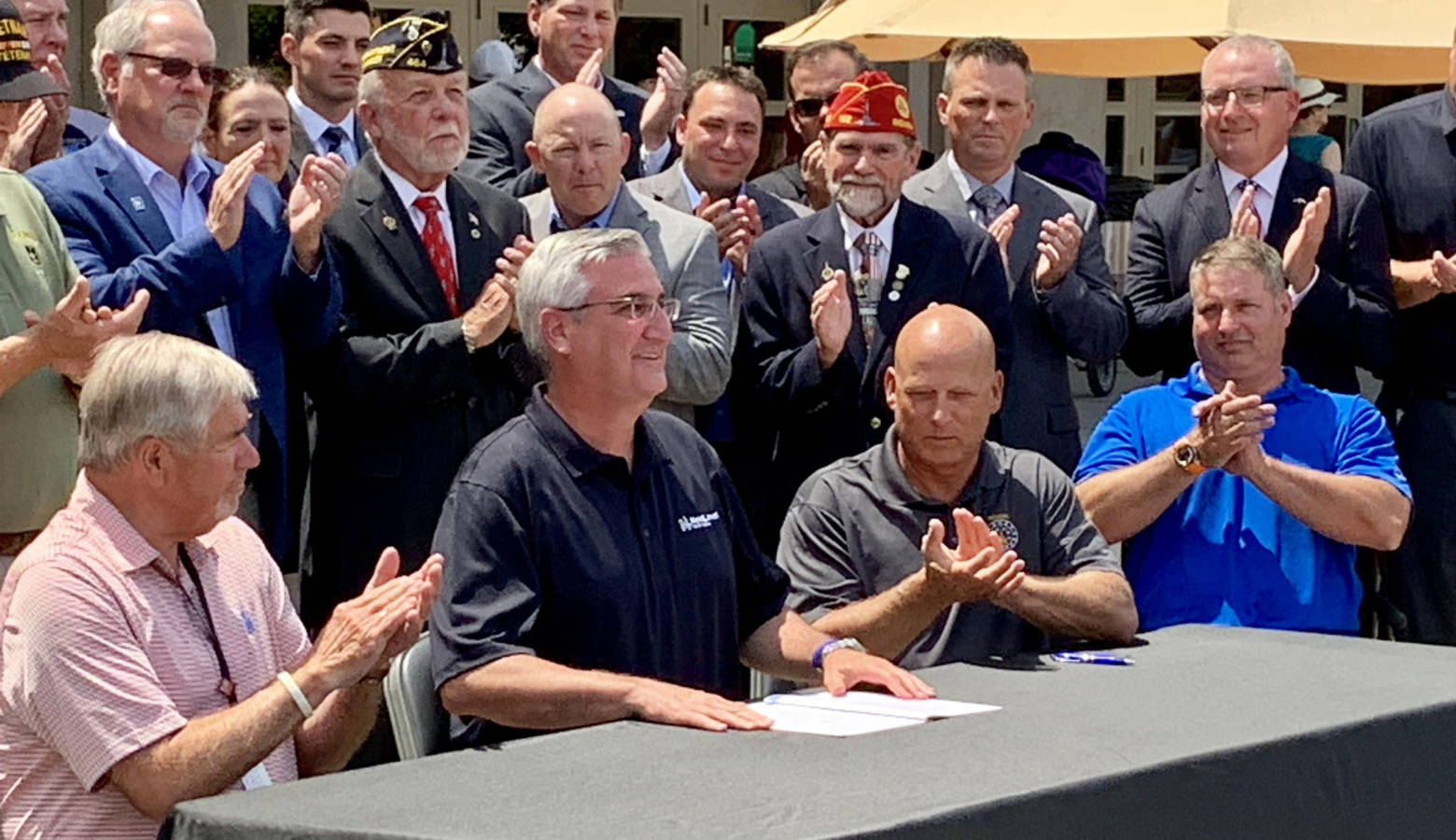 Gov. Eric Holcomb, seated center, at a ceremonial bill signing for the military pension tax exemption. (Brandon Smith/IPB News)