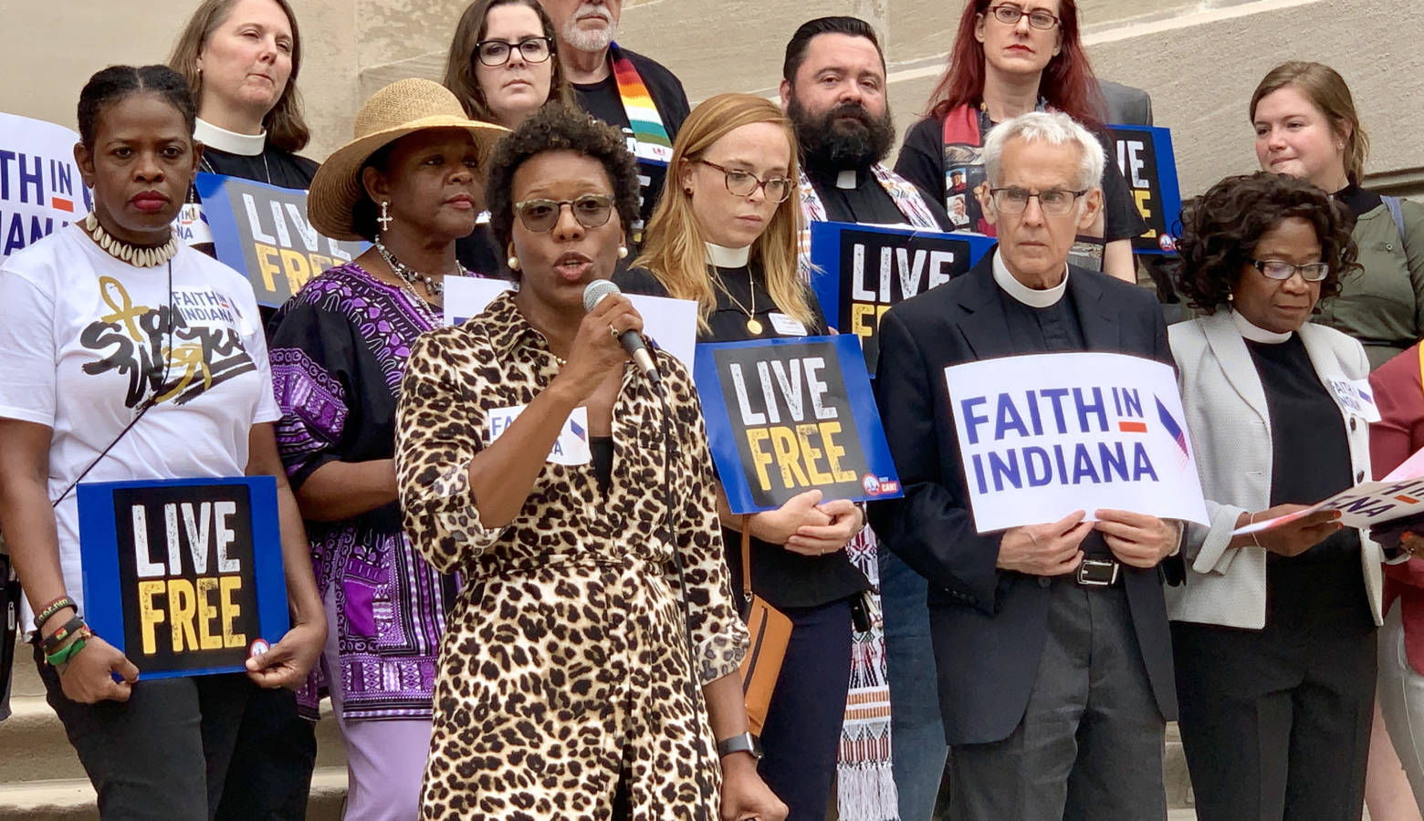 Shonda Nicole Gladden, holding the microphone, speaks on the Indiana Statehouse steps with members of Faith in Indiana. (Brandon Smith/IPB News)