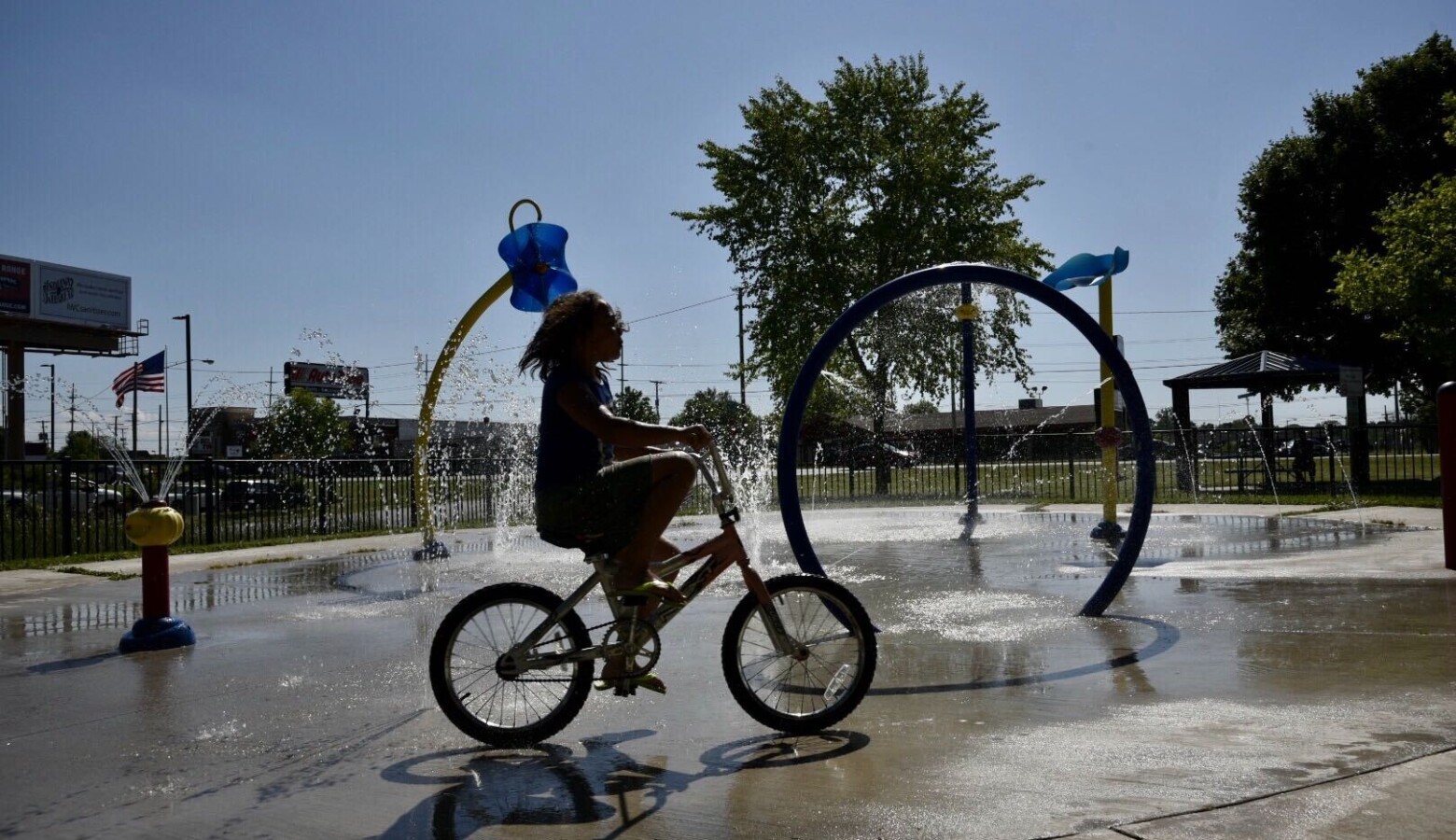 A young child rides a bike at a splash pad in South Bend. (Justin Hicks/IPB News)