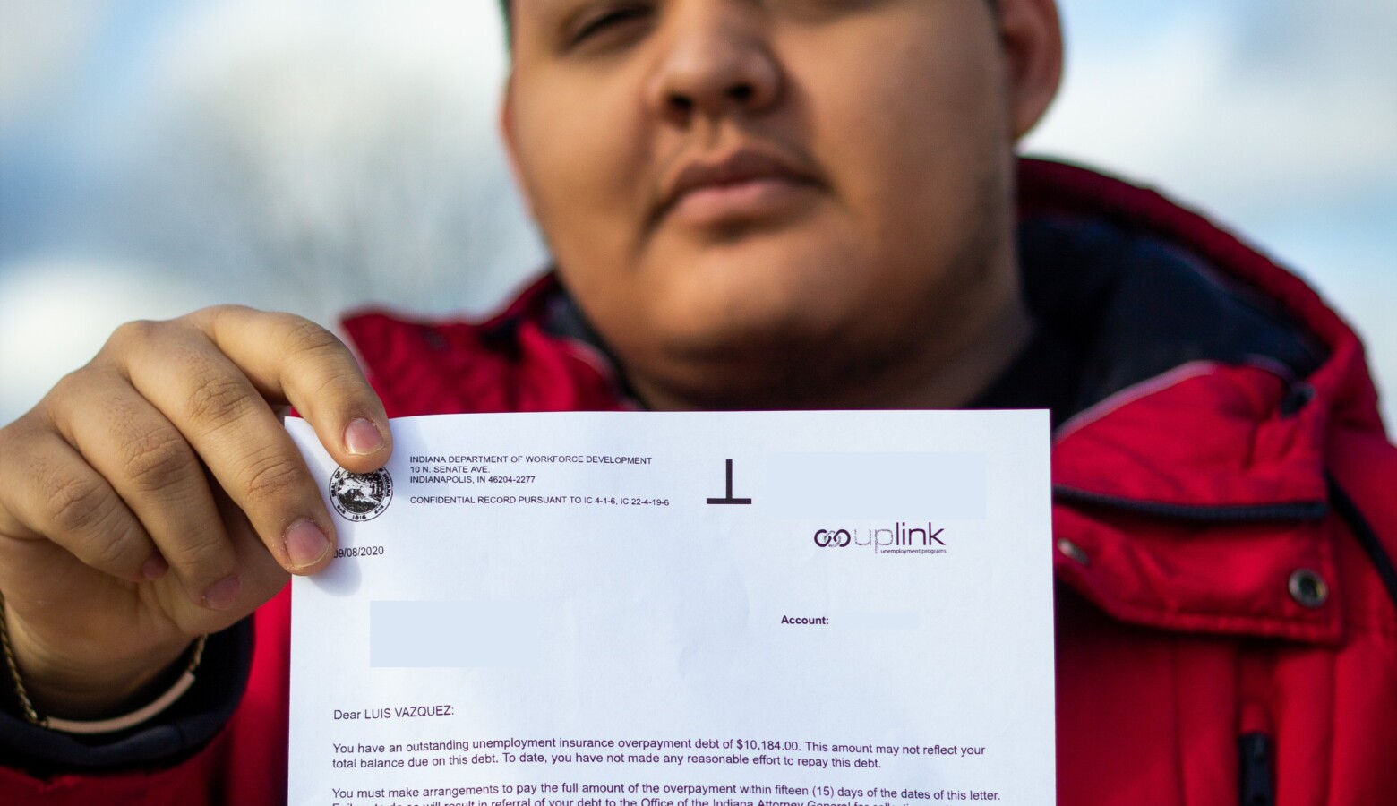 Luiz Vazquez holds a letter from the Department of Workforce Development saying he owes back over $10,000 in unemployment benefits. (Alan Mbathi/IPB News)