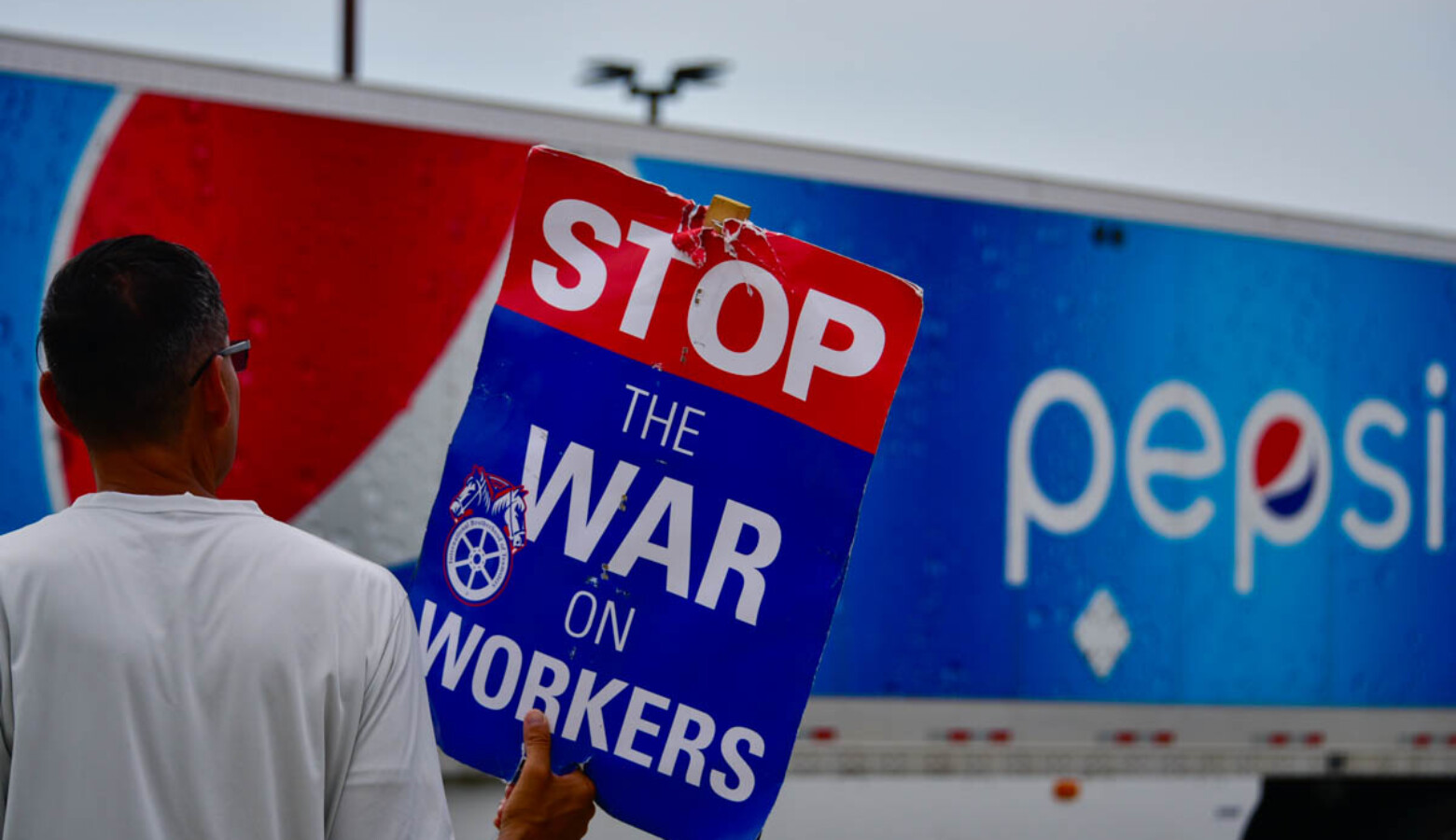 A union worker pickets outside a Pepsi bottling facility in Munster as a truck leaves the driveway. (Justin Hicks/IPB News)