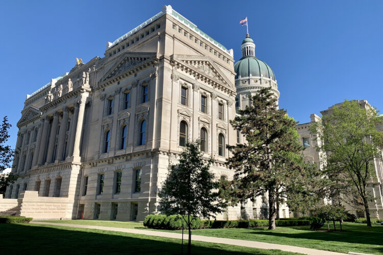 The Indiana Statehouse with trees standing in front of it.