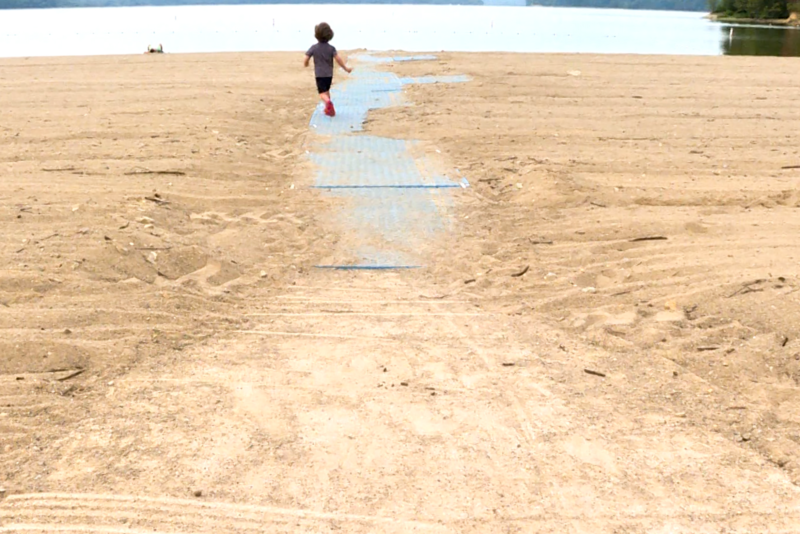 A child runs down a beach mat at Paynetown State Recreation Area in Bloomington.