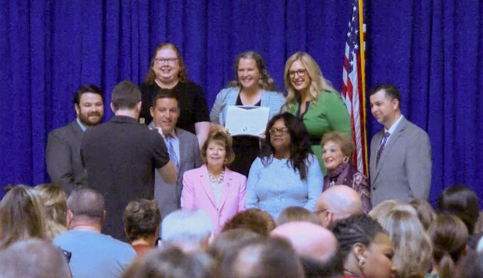 People stand in front of a blue curtain and smile for a camera.