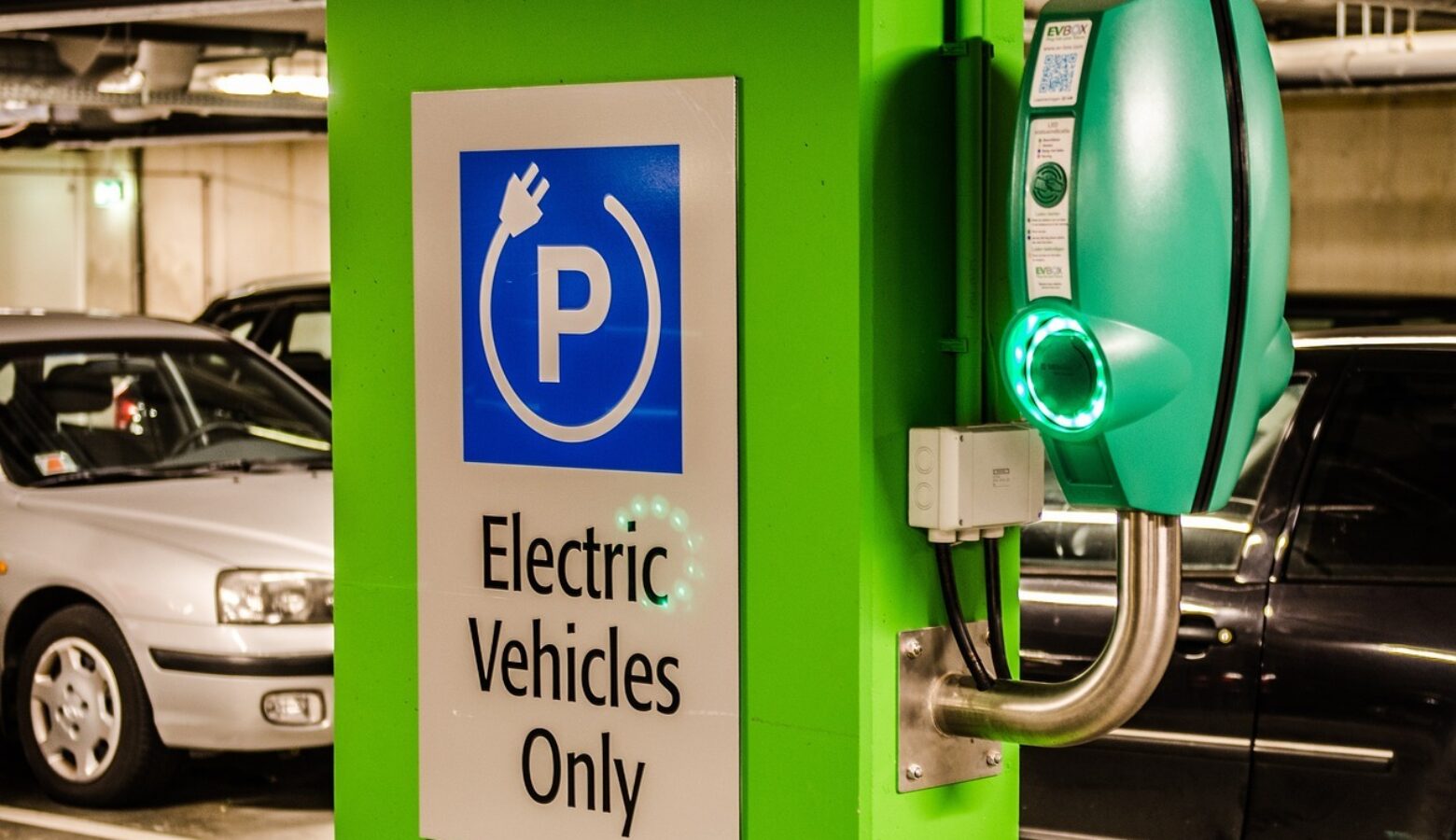 A charging station for electric vehicles inside a parking garage with a sign that reads "electric vehicles only."