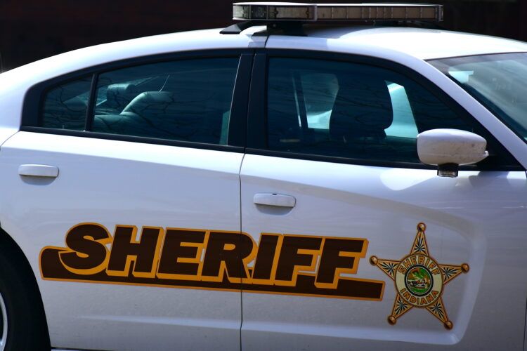 A law enforcement vehicle with "Sheriff" and a star symbol along its side.