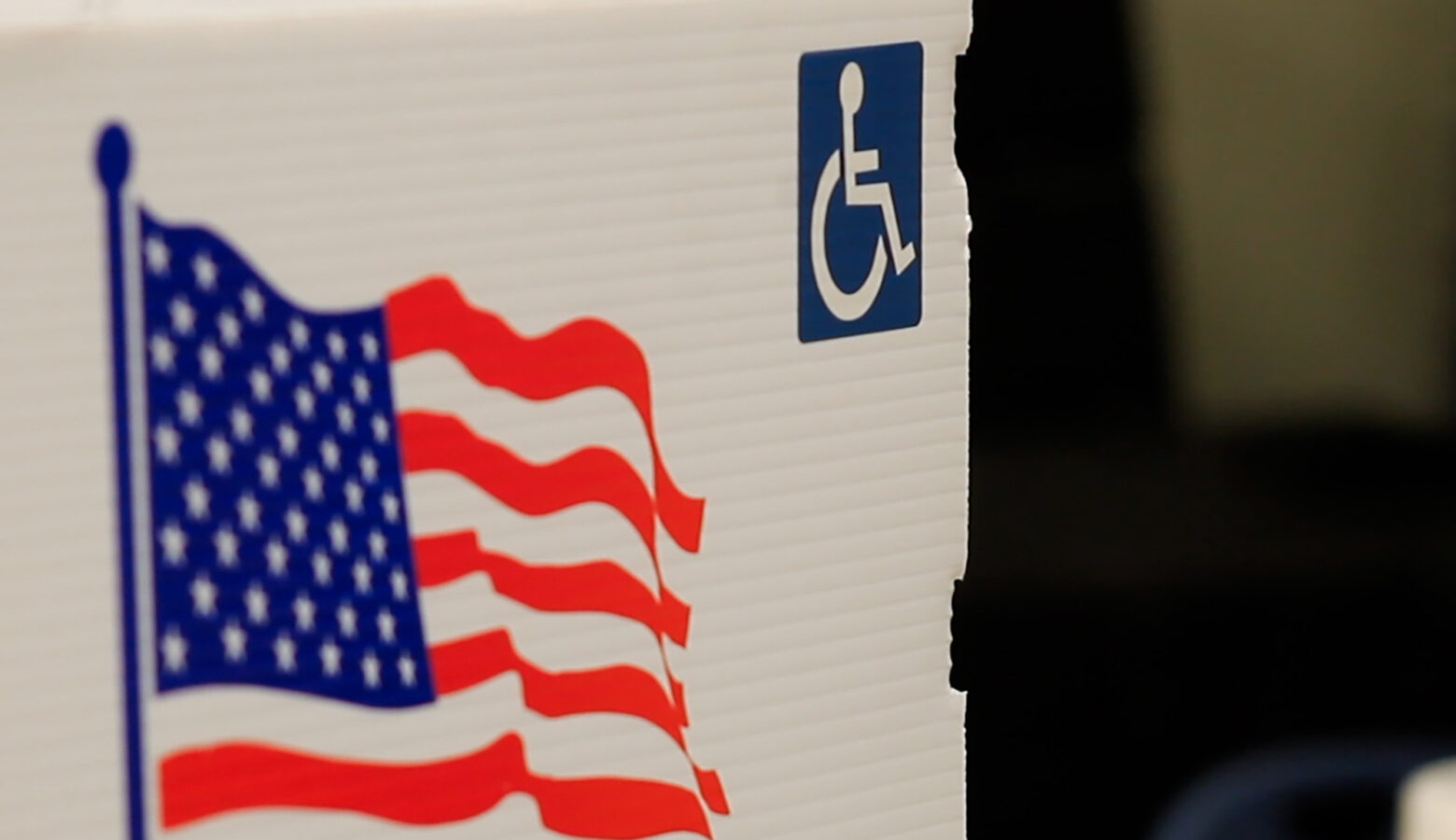 A voter screen is decorated with an American flag and a handicap logo.