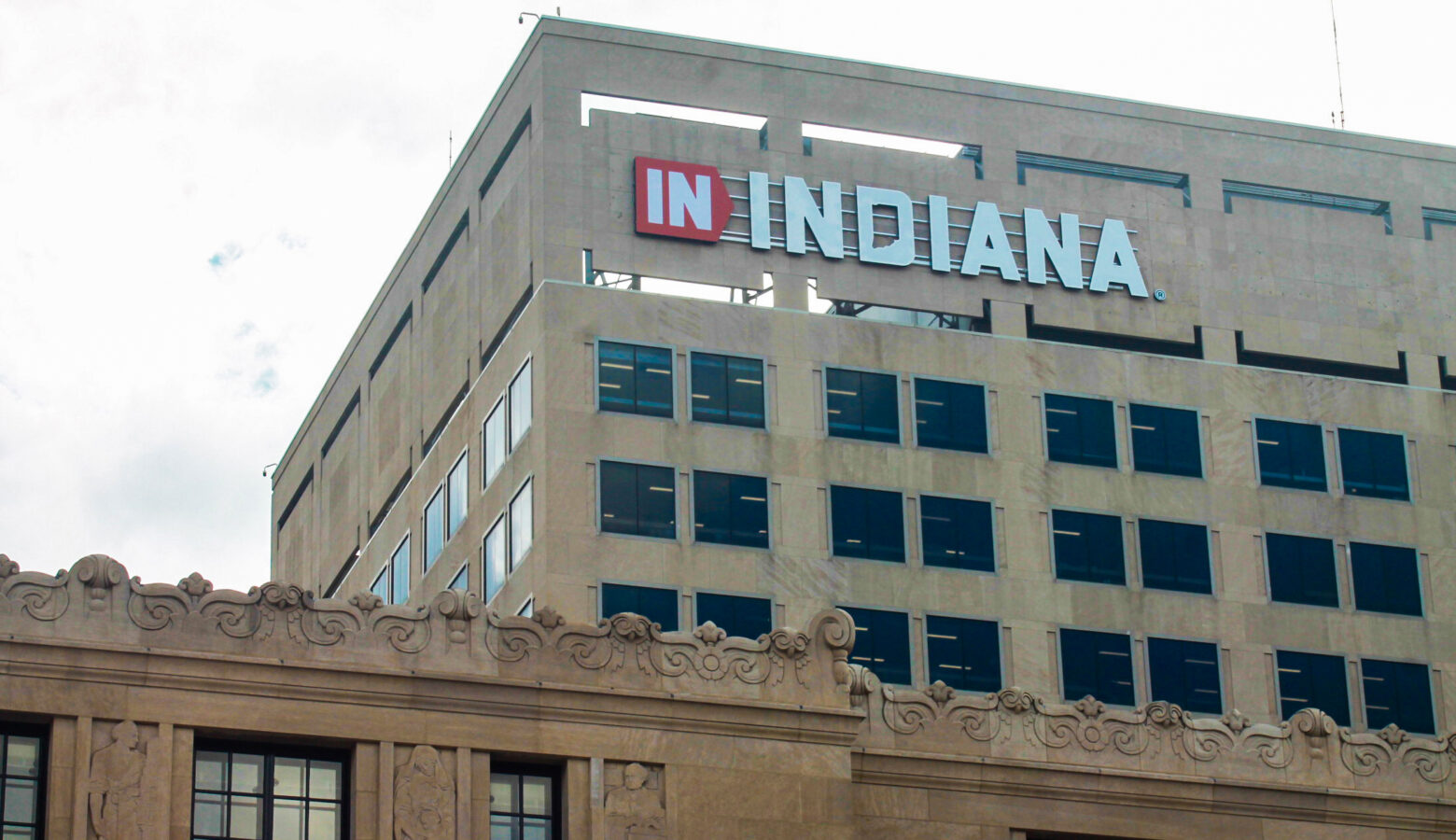 A brown building with an orange polygon with IN and outside of the polygon INDIANA spelled in capitalized white letters on the top left corner of the building.