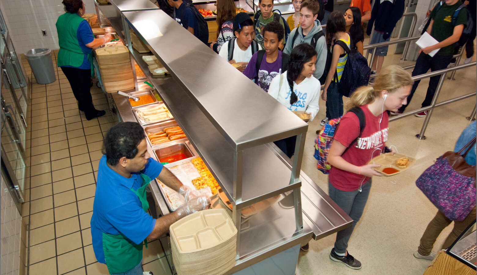 Students with trays get food in a school cafeteria.