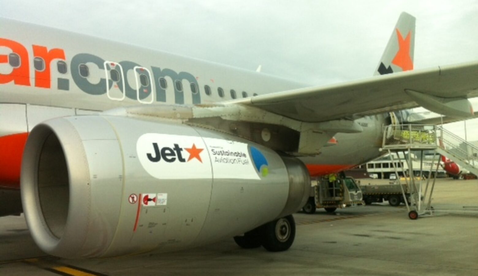 Australian Jetstar Airways has its first flight using biofuels in 2012 using half recycled cooking oil and half traditional jet fuel. A jet sits on a tarmack and on its engine is a sticker with the Jetstar logo and 'sustainable aviation fuel' on it.